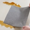 Wycieranie rozlanego płynu z płytek za pomocą grafitowej ściereczki z mikrofibry CZYŚCIOSZEK.