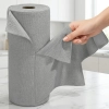Kobieca dłoń odrywająca jedną szarą ściereczkę z mikrofibry ze stojącej pionowo rolki na jasnym kuchennym blacie.