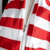 Detal pościeli w biało-czerwone paski z mikrofibry prezentujący praktyczny, starannie wszyty biały ukryty zamek błyskawiczny z metalowym suwakiem