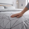 Zbliżenie na miękki materiał satyny bawełnianej z wyraźnym linearnym motywem geometrycznym na szarym tle
