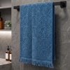 Niebieski, miękki ręcznik frotte Lana o wymiarach 50x100 cm z grubym, tłoczonym wzorem i frędzlami, powieszony w nowoczesnej łazience.