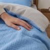 Detal tkaniny dwustronnego muślinu bawełnianego ukazujący kontrast między błękitną a jasnoszarą fakturą pofalowanego materiału