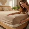 Kobieta zakładająca beżowe prześcieradło nieprzemakalne frotte z gumką na materac w przytulnej sypialni, polski producen
