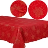 Stół udekorowany czerwonym obrusem świątecznym w srebrne wzory i świecami
