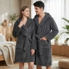 Uśmiechnięta para w łazience ubrana w grube ciemnoszare szlafroki kąpielowe z kapturem z miękkiej mikrofibry