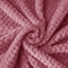 Tekstura miękkiej mikrofibry szlafroka w kolorze pudrowego różu ułożona w przestrzenną falę ukazująca gęstość materiału