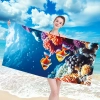 Uśmiechnięta kobieta w bikini trzymająca poziomo rozłożony duży ręcznik plażowy z mikrofibry z motywem podwodnego świata