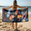 Kobieta na plaży trzymająca rozłożony duży ręcznik plażowy z mikrofibry z nadrukiem trzech dużych motyli. Sklep TwójDomNa5.pl