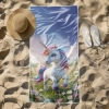 Odporny na piasek ręcznik z mikrofibry z magicznym jednorożcem wśród kwiatów, rozłożony na plaży z białym kapeluszem. TwójDomNa5.pl