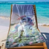 Ręcznik plażowy z mikrofibry w tęczowego jednorożca, zawieszony na drewnianym leżaku na rajskiej plaży z jasnym piaskiem.
