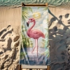 Egzotyczny ręcznik plażowy z motywem flaminga rozłożony na drewnianym leżaku stojącym na piasku nad brzegiem morza.