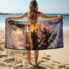 Kobieta stojąca tyłem trzymająca rozłożony gigantyczny ręcznik plażowy z mikrofibry z nadrukiem zachodu słońca - TwójDomNa5.pl
