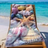Ręcznik plażowy XXL 100x180 z trójwymiarową rozgwiazdą i muszlami rozłożony na leżaku na tle rajskiej plaży