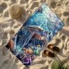 Wielki ręcznik plażowy Serena z pływającym żółwiem morskim, leżący na piaszczystej plaży obok słomkowego kapelusza