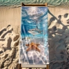 Ogromny ręcznik plażowy XXL z motywem podwodnego świata rozłożony w całości na drewnianym leżaku na plaży