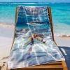 Ręcznik plażowy XXL 100x180 z błękitną, podwodną grafiką rozłożony na leżaku na tle lazurowej wody - TwójDomNa5.pl