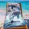 Ręcznik plażowy XXL 100x180 z fotorealistyczną grafiką delfinów rozłożony na leżaku na tle lazurowej wody - TwójDomNa5.pl