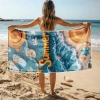 Kobieta stojąca tyłem trzymająca rozłożony ręcznik z mikrofibry z nadrukiem letniej plaży, oceanu i klapek na tle morza
