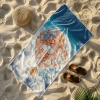 Wielki ręcznik plażowy Serena z motywem cukierkowego balonu leżący na piaszczystej plaży obok słomkowego kapelusza i klapek - TwójDomNa5.pl