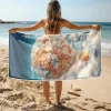 Kobieta stojąca tyłem trzymająca rozłożony gigantyczny ręcznik plażowy z mikrofibry ze słodkim wzorem balonu pełnego cukierków na plaży
