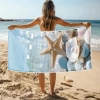 Modelka na plaży trzymająca rozłożony ręcznik z mikrofibry ze wzorem rozgwiazdy i perły