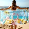 Kobieta na plaży trzymająca rozłożony ręcznik szybkoschnący z motywem dmuchanych kół w paski