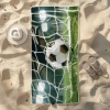 Ręcznik plażowy Sand-Free z piłką w bramce leżący na piasku obok sandałów