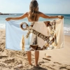 Kobieta tyłem trzymająca rozłożony duży ręcznik XXL z motywem kotwicy na plaży - TwójDomNa5.pl