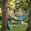 Para wieszająca hamak turystyczny między drzewami w parku