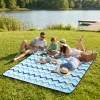Rodzina z dwójką dzieci relaksująca się nad jeziorem na dużym, niebieskim kocu WONDER we wzór zygzaków.