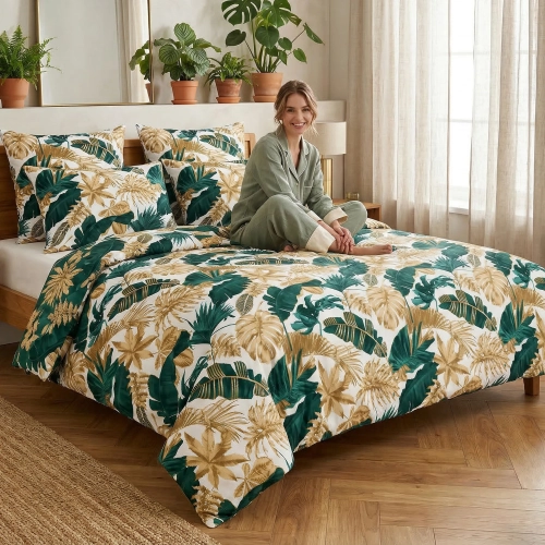 Uśmiechnięta kobieta w szałwiowej piżamie siedzi na łóżku z elegancką, tropikalną pościelą z bawełny premium J&W w szmar