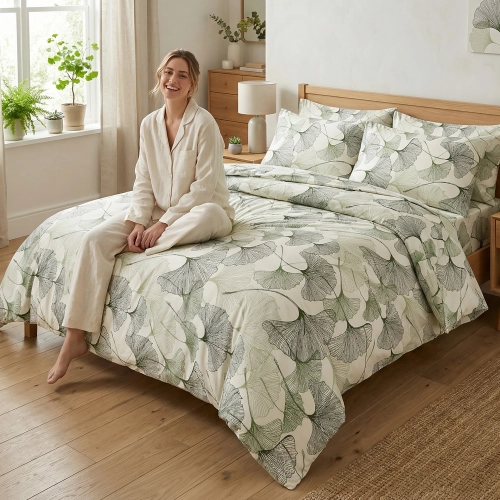 Łóżko zaścielone w elegancką, białą pościel bawełnianą z botanicznym motywem liści miłorzębu J&W, w jasnej sypialni.