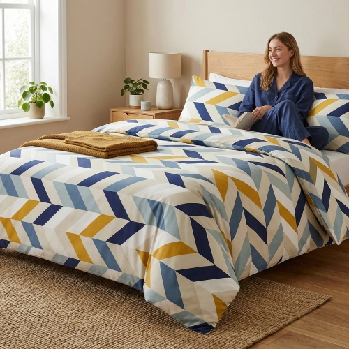 Uśmiechnięta kobieta w granatowej piżamie siedzi z książką na łóżku z nowoczesną pościelą z bawełny premium J&W w geomet