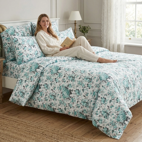 Kobieta w kremowych piżamach lnianych czyta książkę na łóżku z bawełnianą pościelą J&W Klasyczny Turkusowy Ogród.