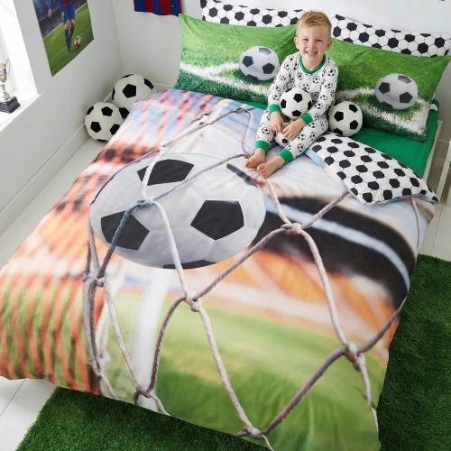 Chłopiec relaksujący się na łóżku z wesołą, wygodną pościelą bawełnianą J&W we wzór piłkarski.