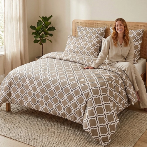 Kobieta w luksusowej sypialni siedzi na łóżku z elegancką pościelą z bawełny J&W z motywem beżowej marokańskiej koniczyn