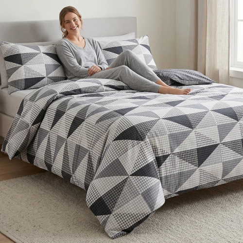 Kobieta uśmiecha się, odpoczywając na łóżku z piękną, nowoczesną pościelą J&W we wzór geometryczny.