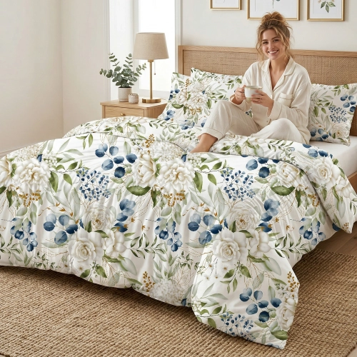 Uśmiechnięta kobieta siedzi na łóżku z piękną, botaniczną pościelą J&W we wzór kwiatów i eukaliptusa.