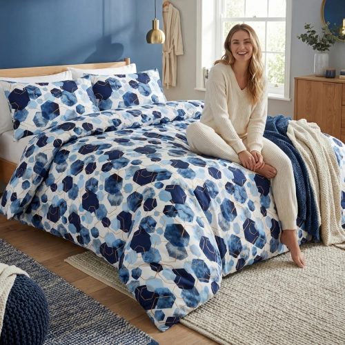 Kobieta relaksująca się na łóżku z biało-granatową, bawełnianą pościelą J&W we wzór geometrycznych heksagonów.