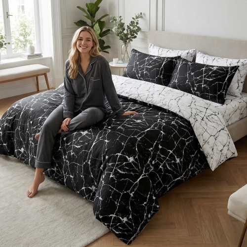 Kobieta relaksująca się na łóżku z czarno-białą, dwustronną pościelą bawełnianą J&W we wzór żyłek marmuru.