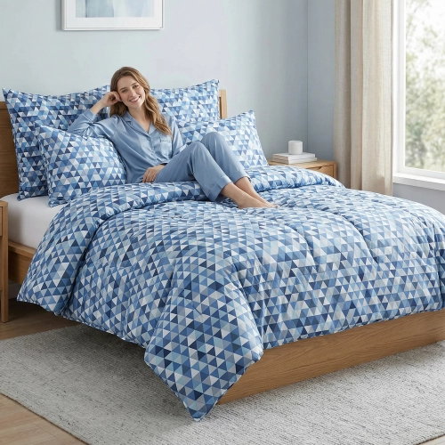 Łóżko zaścielone w elegancką pościel z bawełny J&W we wzór niebieskich trójkątów, w jasnej sypialni.