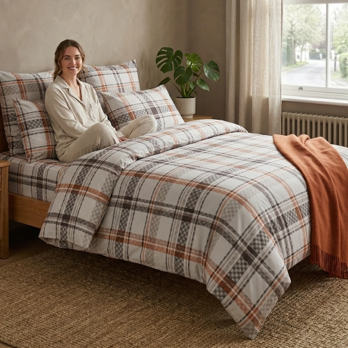 Wygodne łóżko w jasnej sypialni, zaścielone w pościel bawełnianą J&W we wzór brązowej kraty.