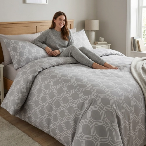 Łóżko w pełnej światła sypialni, zaścielone w elegancką, szarą pościel bawełnianą J&W w geometryczny wzór.