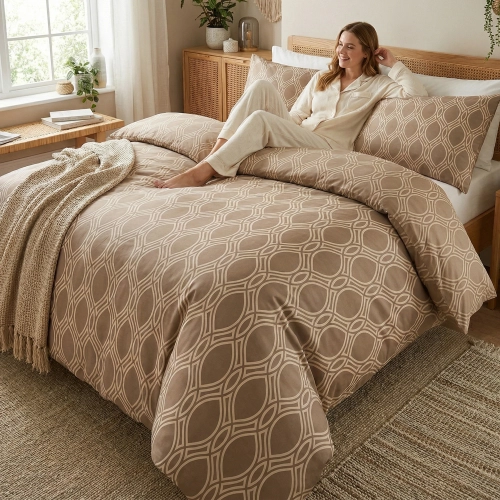 Kobieta relaksująca się na łóżku z beżową, wygodną pościelą bawełnianą J&W we wzór jasnych łezek.