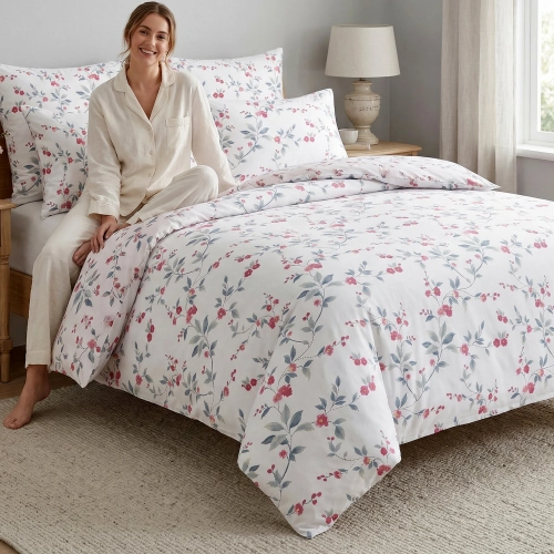 Kobieta relaksująca się na łóżku z białą, wygodną pościelą bawełnianą J&W we wzór wiosennych kwiatów.