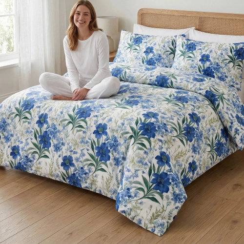 Kobieta relaksująca się na łóżku z białą, wygodną pościelą bawełnianą J&W we wzór letnich, niebieskich kwiatów.