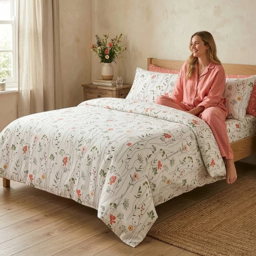 Kobieta na łóżku w sypialni z pościelą w delikatne pnącza i różowe kwiaty