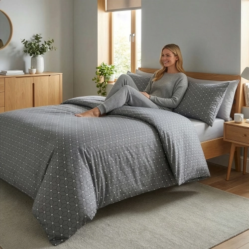 Kobieta relaksująca się na łóżku z pościelą w szare heksagony i białe kropki