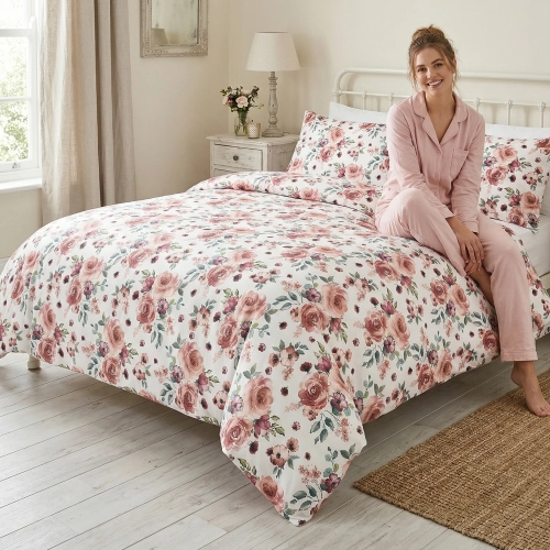 Kobieta relaksująca się na łóżku z jasną, wygodną pościelą bawełnianą J&W we wzór letnich, romantycznych kwiatów.