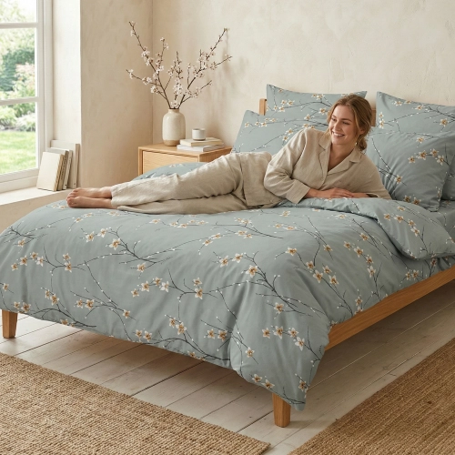 Uśmiechnięta kobieta relaksująca się na łóżku w szałwiowej pościeli w kwitnące gałązki z kolekcji Szałwiowy Szept